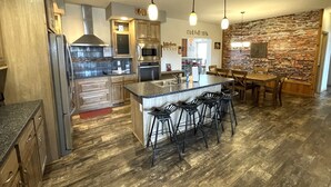 A modern kitchen with a central island, bar stools, and a stone accent wall.