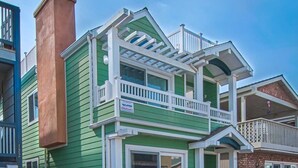 A two-story building with a green exterior, white trim, and a balcony.