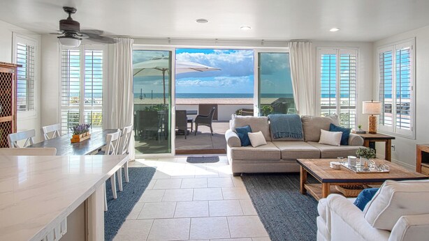 A spacious living room with a large sliding glass door leading to a balcony with a beach view. - Lovely lower unit with spectacular oversized patio right on the sand! (Newport Beach)