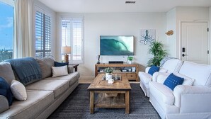 A modern living room with a grey sofa, a white sofa, a wooden coffee table, and a TV on the wall. - Lovely lower unit with spectacular oversized patio right on the sand! (Newport Beach)