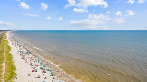 A beach with numerous umbrellas and people, a clear sky, and calm water. - *Fall into Savings-20% Off New Bookings thru 2026* (Myrtle Beach)