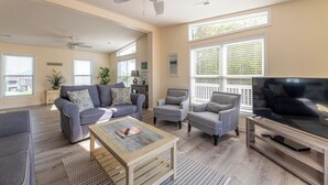 A living room with a sofa, armchairs, a coffee table, a TV, and a ceiling fan.