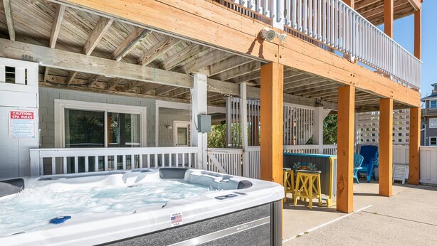 A hot tub outside a building with a wooden deck and a sign indicating spa rules.