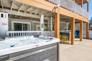 A hot tub outside a building with a wooden deck and a sign indicating spa rules.