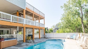 A backyard with a swimming pool, wooden deck, and outdoor seating area.