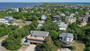 A coastal residential area with houses surrounded by dense greenery.