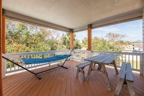 Una terraza de madera con una hamaca, una mesa de picnic y bancos.