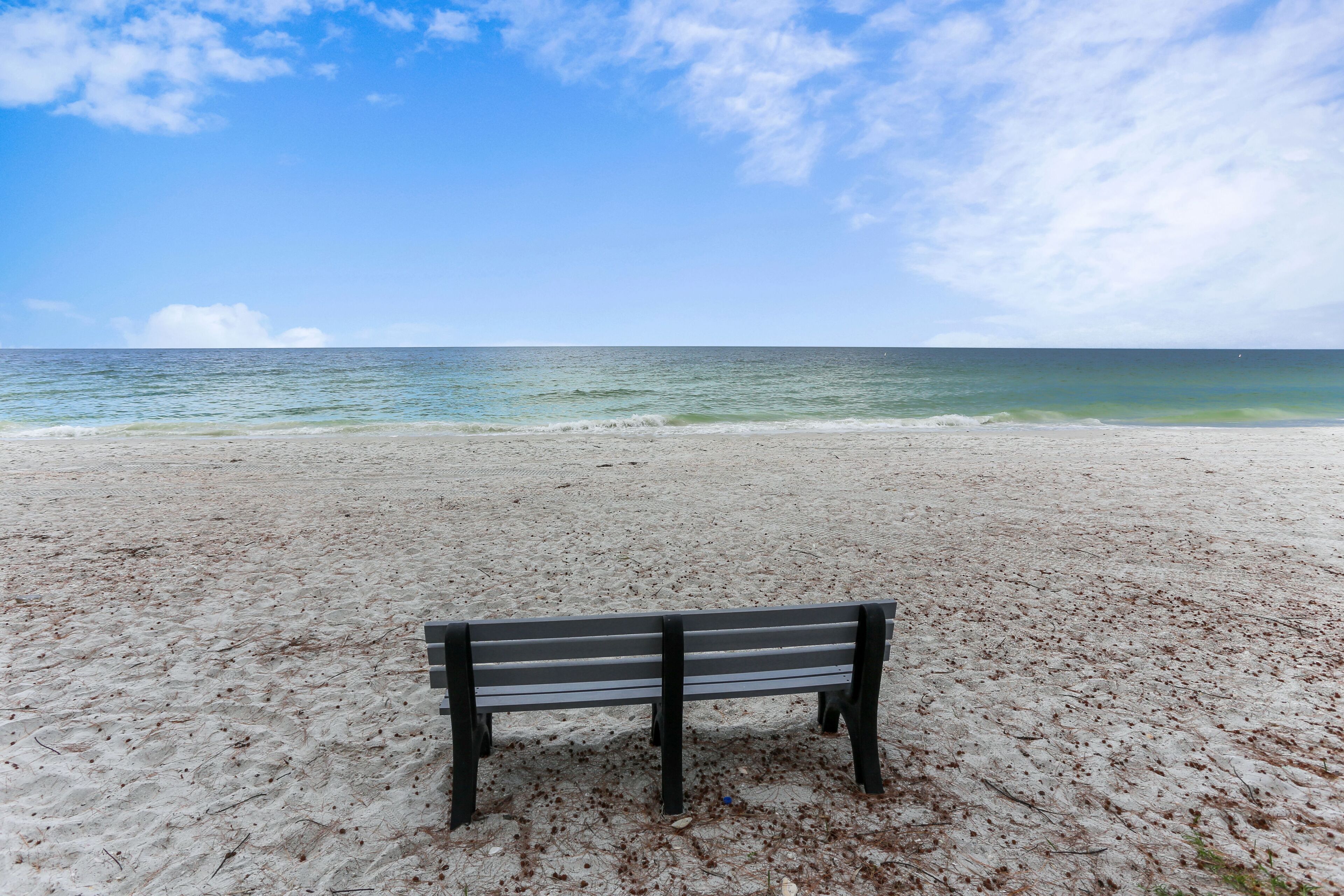 A beach with a single bench facing the ocean.