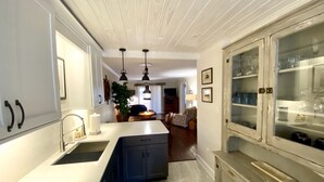 A kitchen with a central island, pendant lighting, and a dining area with a sofa and table.