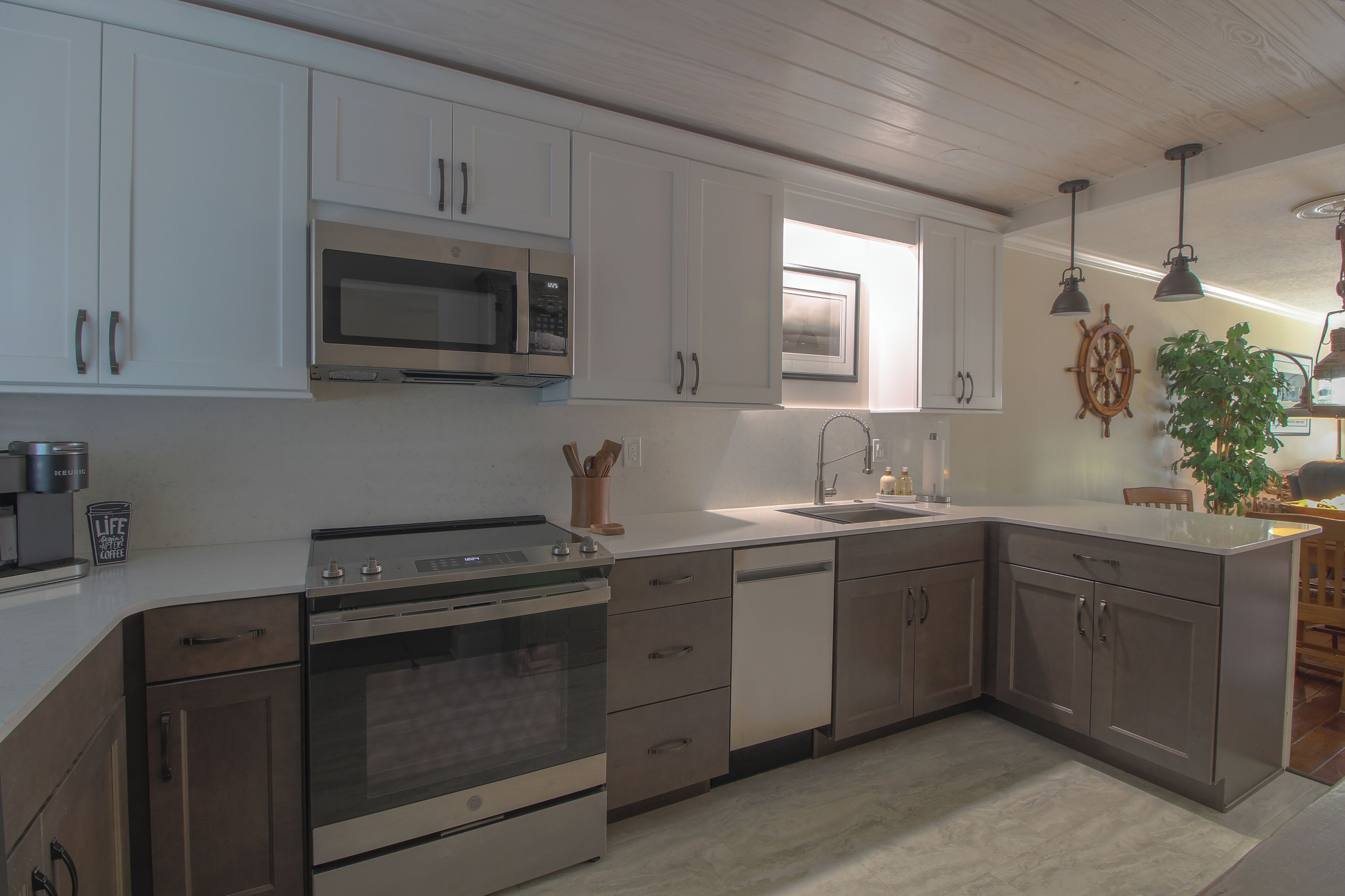 A modern kitchen with stainless steel appliances, white cabinetry, and a central island with a sink.