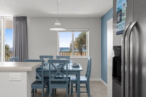 A modern kitchen with a dining area, large windows, and a view of the sea. - DP 201: Emerald Escape - Endless Sunshine, Ocean Breezes – Your Condo Awaits! (Fort Walton Beach)