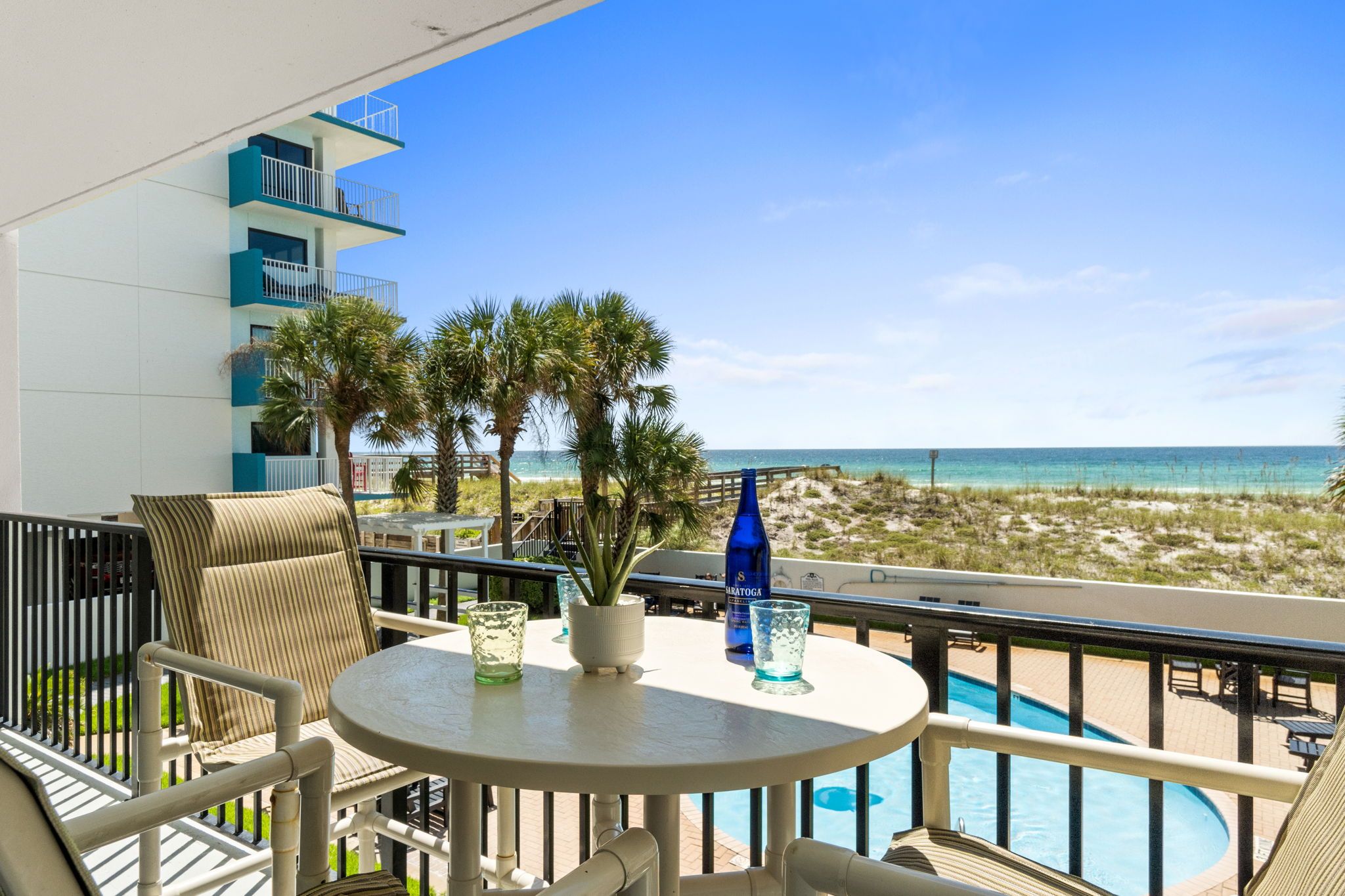 Un balcone con piscina, sedie a sdraio e vista sulla spiaggia.