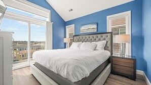 Un dormitorio con una cama grande, vistas desde un balcón y un cuadro en la pared.
