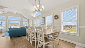 Un comedor amplio con techo alto, ventanas grandes y vistas al exterior.