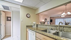 A kitchen with granite countertops, stainless steel sinks, and wooden cabinets. - Ocean Springs Condo in Waterfront Resort! (Ocean Springs)