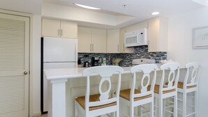 Une cuisine moderne avec des meubles blancs, un four à micro-ondes encastré et un revêtement mural en carreaux.