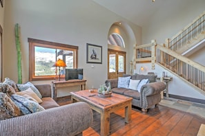 A spacious living room with a wooden coffee table, two sofas, a television, and a staircase. - Breckenridge 'Sky Lodge' w/ Hot Tub + Gas Grill! (Breckenridge)