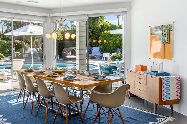 Comedor con una mesa grande, sillas y vistas a una piscina y jardín.