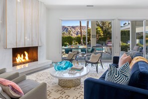 A living room with a fireplace, a pool view, and a comfortable seating area.