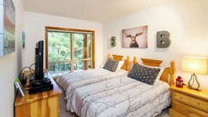A bedroom with two beds, a desk with a computer, a window, and wall art. - Slope Side, Amazing Location, True Ski in & Out (Whistler)