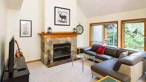 A living room with a fireplace, a sofa, a television, and framed pictures on the wall. - Slope Side, Amazing Location, True Ski in & Out (Whistler)