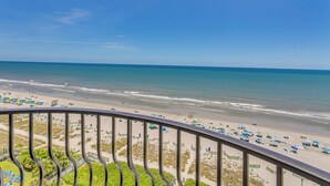 Vista sulla spiaggia dal balcone, con ringhiera, spiaggia sabbiosa e oceano.