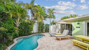 Un jardin avec une piscine, des chaises longues et une table de pique-nique.