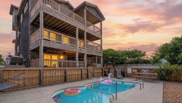Un bâtiment en bois à plusieurs étages, doté d’une piscine et de bouées gonflables.