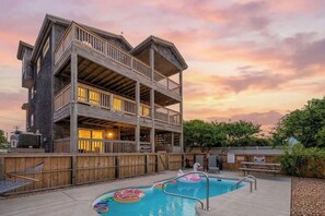 Un bâtiment en bois à plusieurs étages, doté d’une piscine et de bouées gonflables.