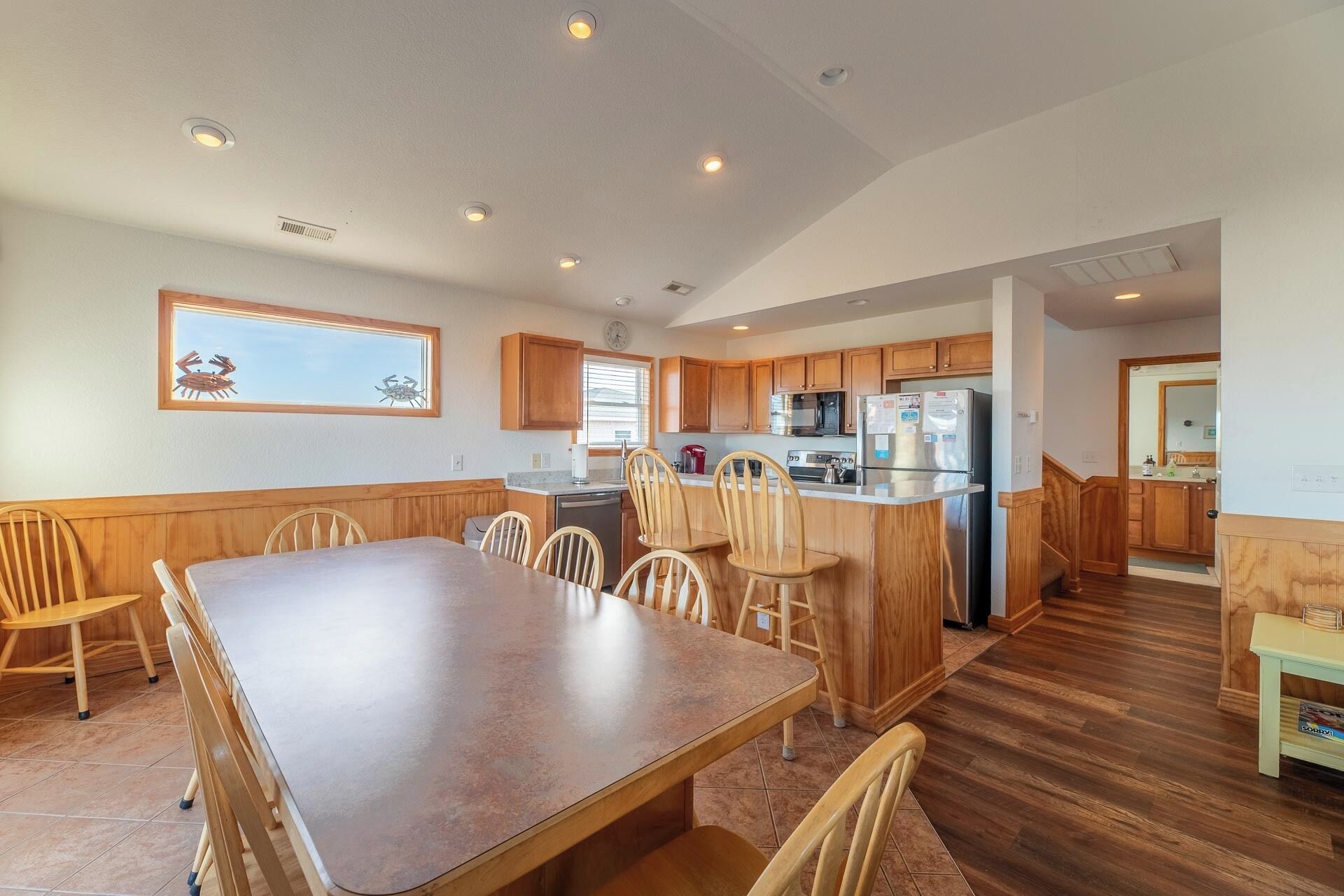 A spacious kitchen with wooden cabinets, a large island, and a dining area with a long table and chairs.