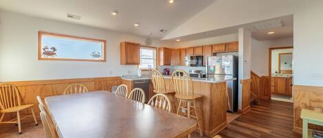 A spacious kitchen with wooden cabinets, a large island, and a dining area with a long table and chairs.
