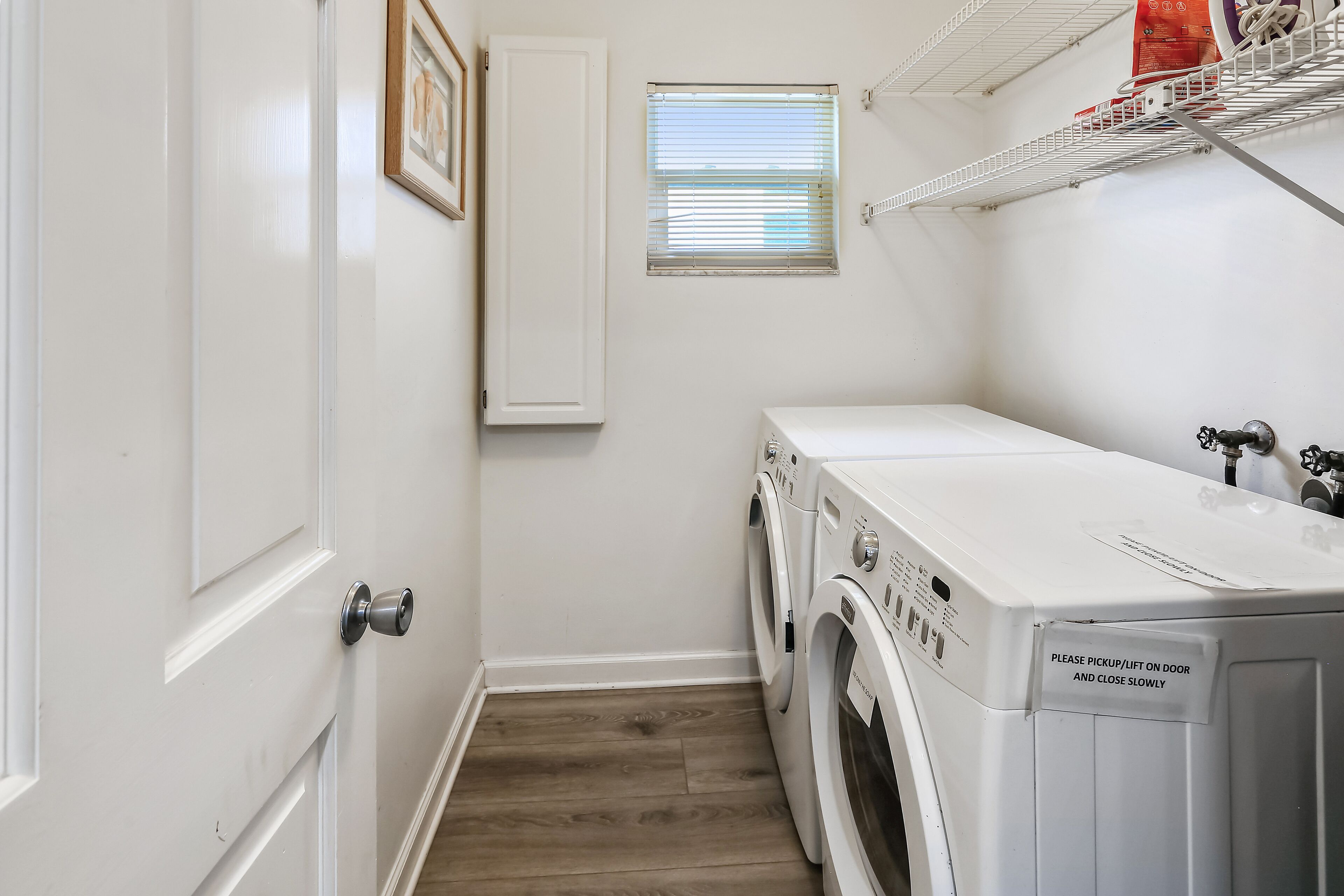 A laundry room with a door, a window, and a shelf with items.