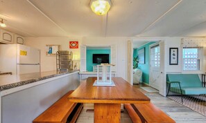 Una cocina con una mesa de madera, un refrigerador y una pared color turquesa.