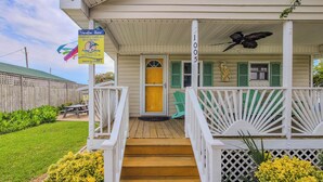 A wooden house with a porch, a yellow door, and a sign for 'Vacation Here!' - The Cottage - 2 BR Beach Bungalow near Nightlife! (Surf City)