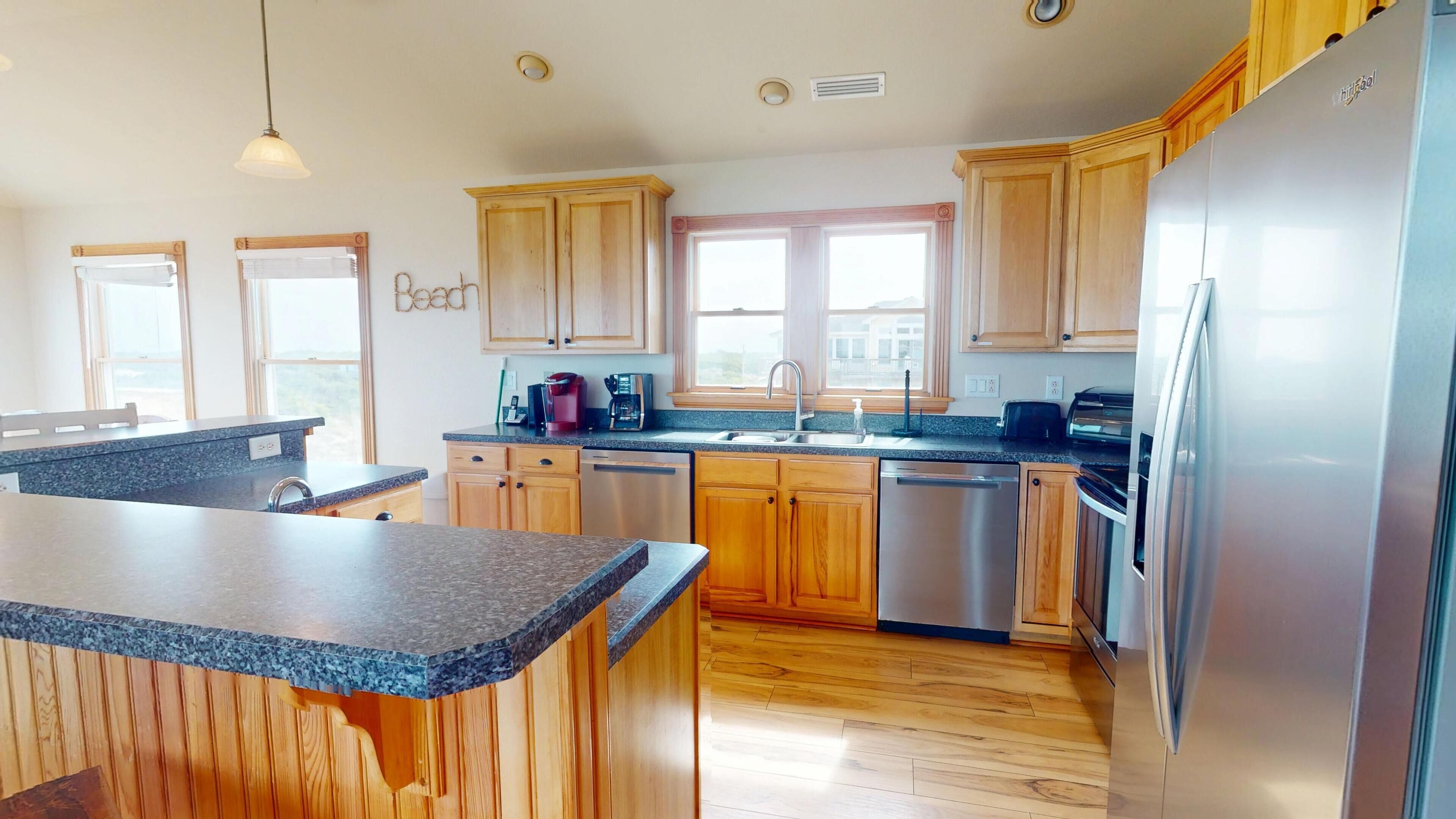 Una cocina moderna con armarios de madera, encimeras de granito, electrodomésticos de acero inoxidable y una isla grande.