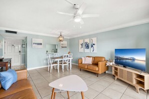 A living room with a sofa, TV, and a dining area with chairs and a table.