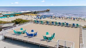 Une terrasse au bord de la plage, avec des sièges extérieurs et une vue sur l’océan.
