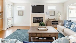 A living room with a fireplace, a television mounted above it, a sofa, and a coffee table.