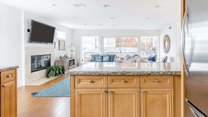 A modern kitchen with wooden cabinets, a granite countertop, and a stainless steel refrigerator.