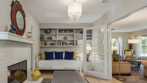 Ein Zimmer mit Kamin, einer Couch, einem Bücherregal und einer Deckenleuchte.