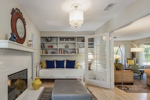 A room with a fireplace, a sofa, a bookshelf, and a chandelier.