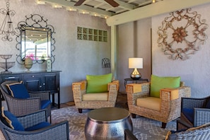 A room with wicker furniture, a mirror, a lamp, and decorative wall art.