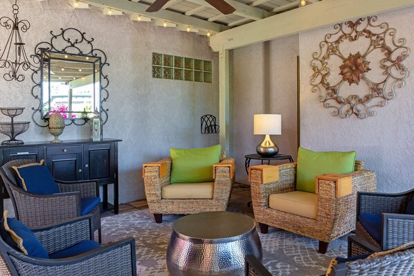 A room with wicker furniture, a mirror, a lamp, and decorative wall art.