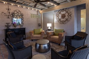 A room with wicker furniture, a round metal table, a mirror, and decorative wall art.