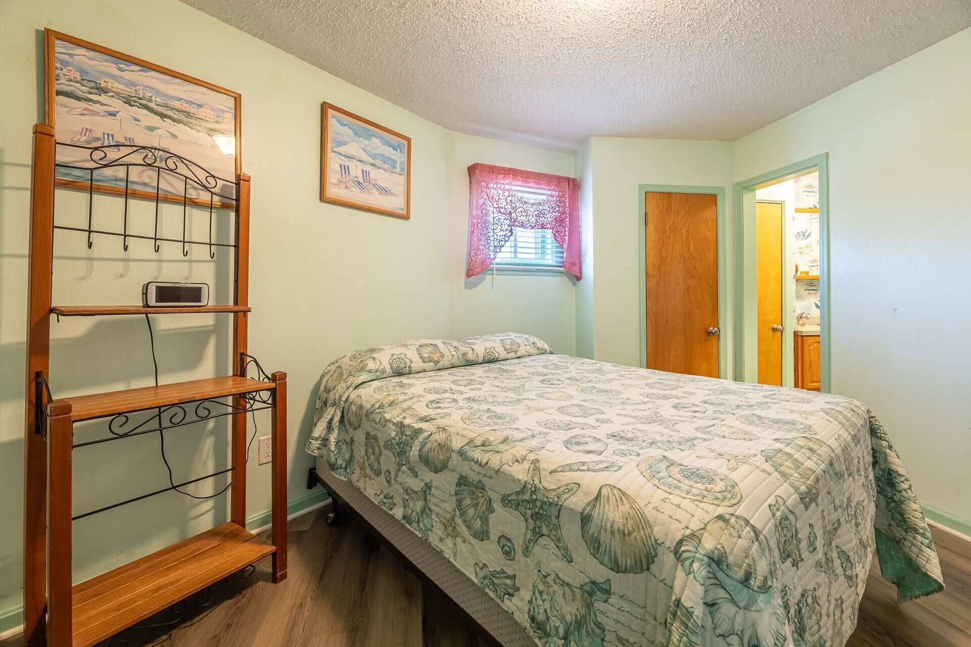 A bedroom with a bed, a wooden shelf unit, and two framed pictures on the wall.