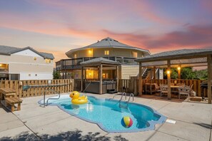 Patio trasero con piscina, jacuzzi y zona de estar al aire libre.