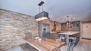 Una cucina moderna con una grande isola, elettrodomestici in acciaio inossidabile e una parete in pietra rustica.