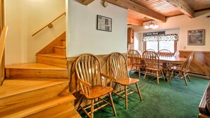 Una escalera de madera que conduce a un comedor con alfombra verde, sillas de madera y un letrero que dice "Down White Heat".