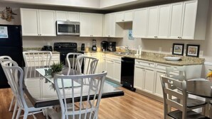 A modern kitchen with white cabinets, a dining table with chairs, and a microwave above the counter.