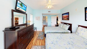 A bedroom with two beds, a dresser, a TV, and a ceiling fan.
